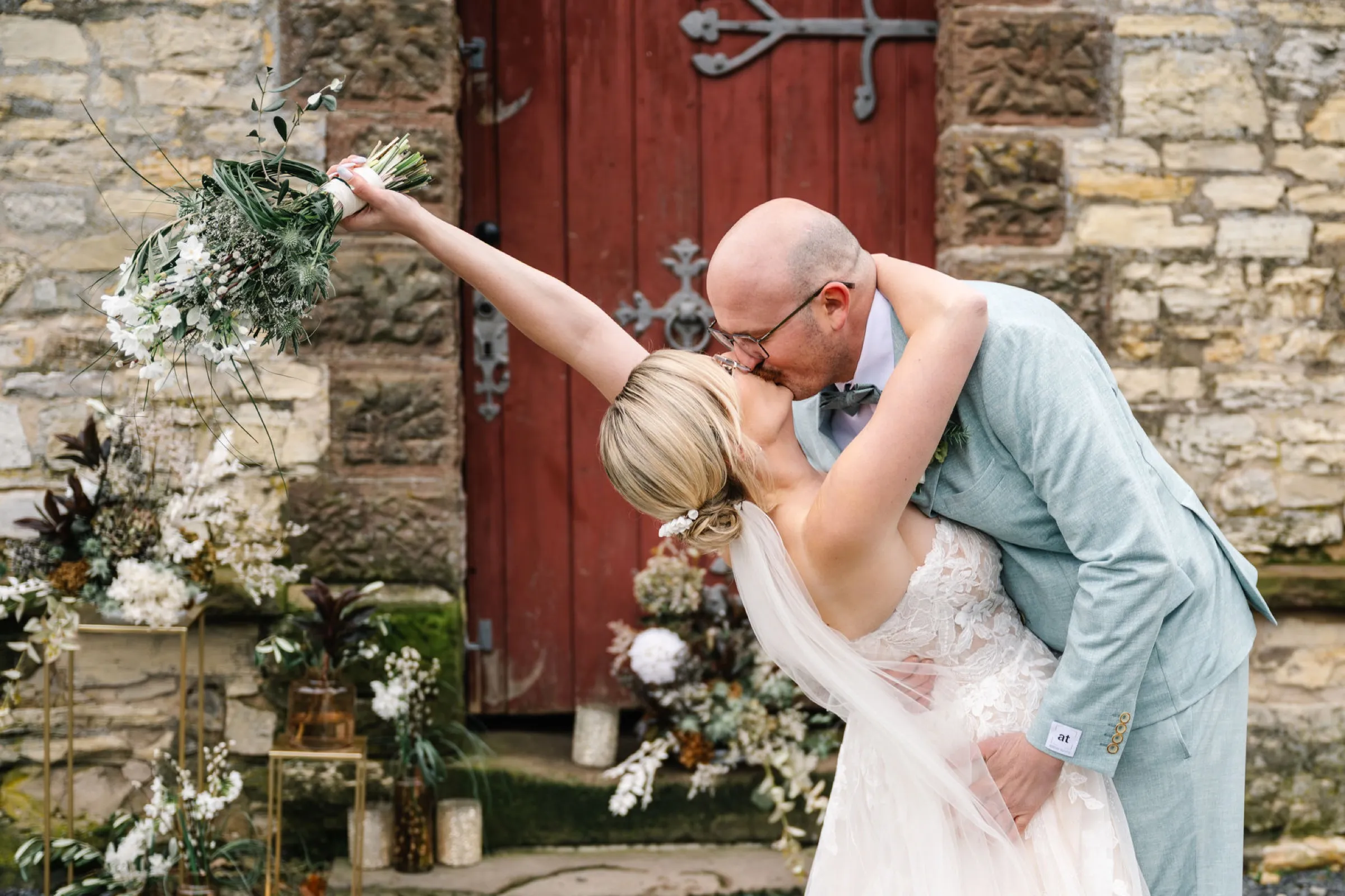 Brautpaar küsst sich vor dem rustikalen roten Tor – Hochzeit im Ausblick am Wieterturm